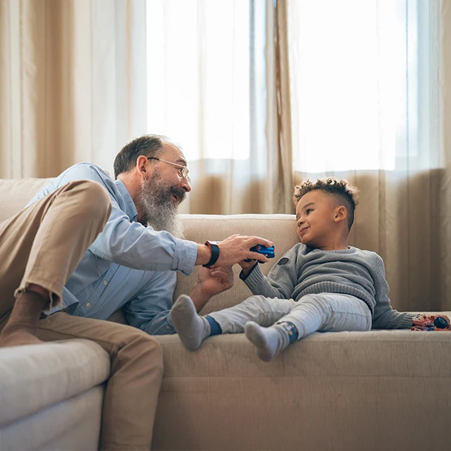 Chiropractic-Senior-Playing-With-His-Grandchild-On-Couch-640x640-HP-Moto.webp