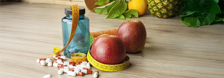 Supplements, fresh fruit, and measuring tape representing holistic weight loss treatments Supplements, fresh fruit, and measuring tape representing holistic weight loss treatments