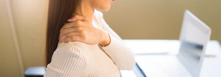 Woman holding neck in pain from poor posture at desk Woman holding neck in pain from poor posture at desk